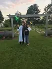 Two people posing together on a lawn after a graduation.