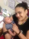 An adult holding a baby beside a window.