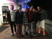 A group gathered outside a brightly lit venue at night.