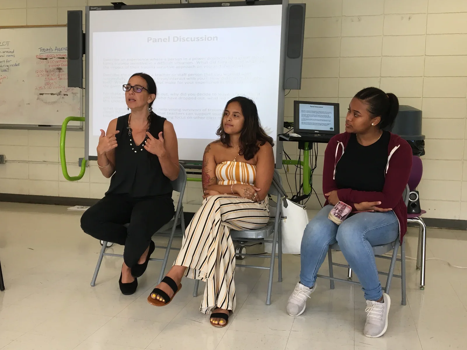 Three participants speaking together in front of a projected presentation.