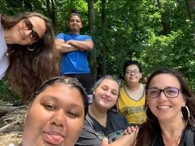 Friends taking a group selfie on a wooded trail.