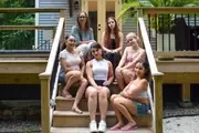 A group gathered on the steps of a wooden porch.
