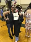 Two people celebrating with a certificate in a gymnasium.