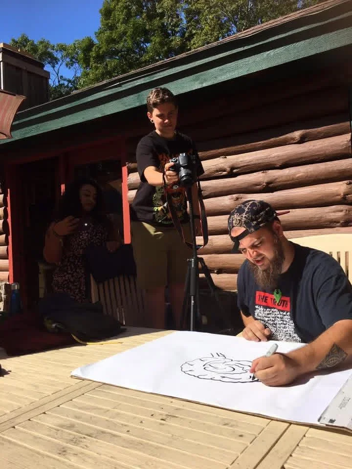 Participants drawing a large poster on a sunny deck.