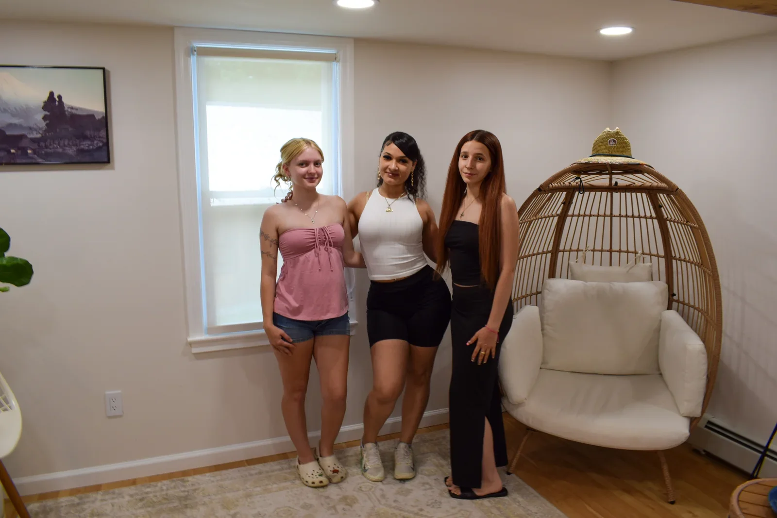 Three participants standing together beside a hanging chair.