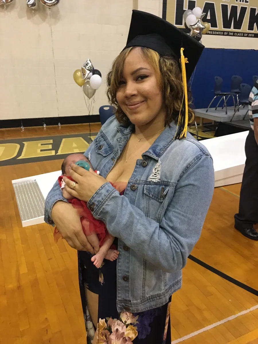 A participant holding a baby during a gathering in a gymnasium.