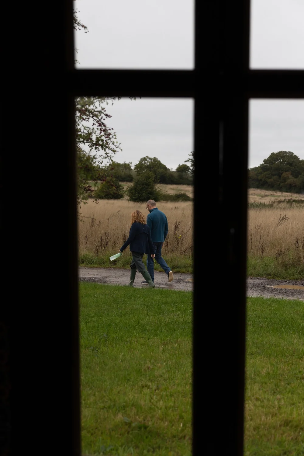 Two guests walking through the meadow, seen through a window