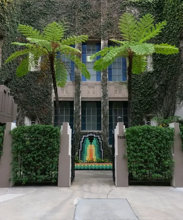 Ivy-covered Los Angeles courtyard apartment building with tree ferns