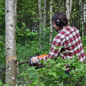 A man using a chainsaw on a tree down while wearing cyber acoustics hearing protection