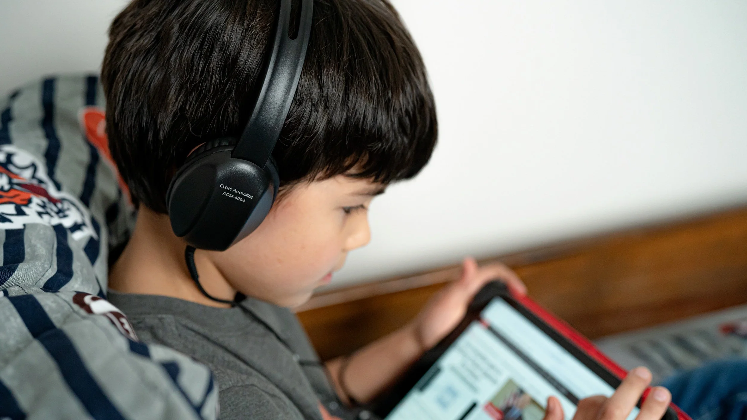 Boy wearing durable ACM-4004 headphones while using a tablet