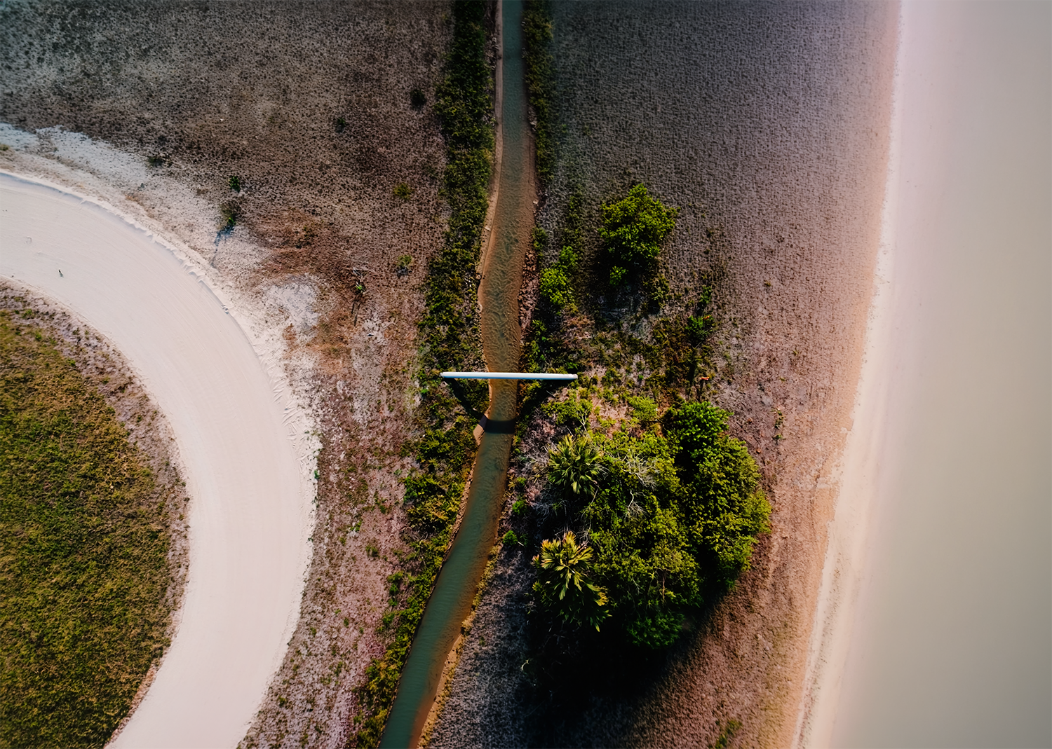 Arial view of a beach road and the shoreline, split by a small river.