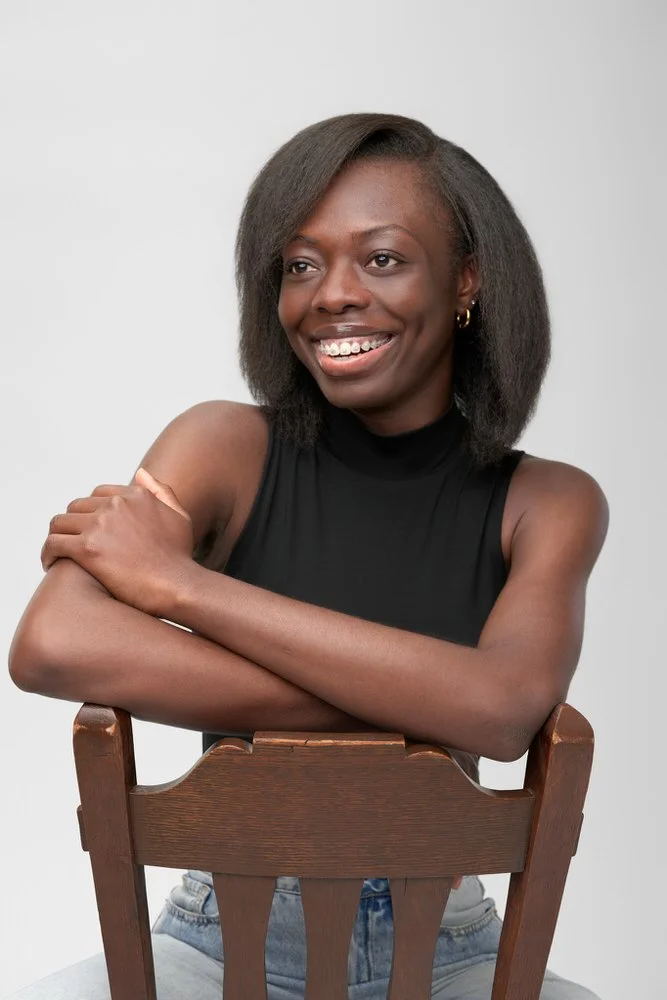 Smiling model headshot in a black mock neck on a white backdrop