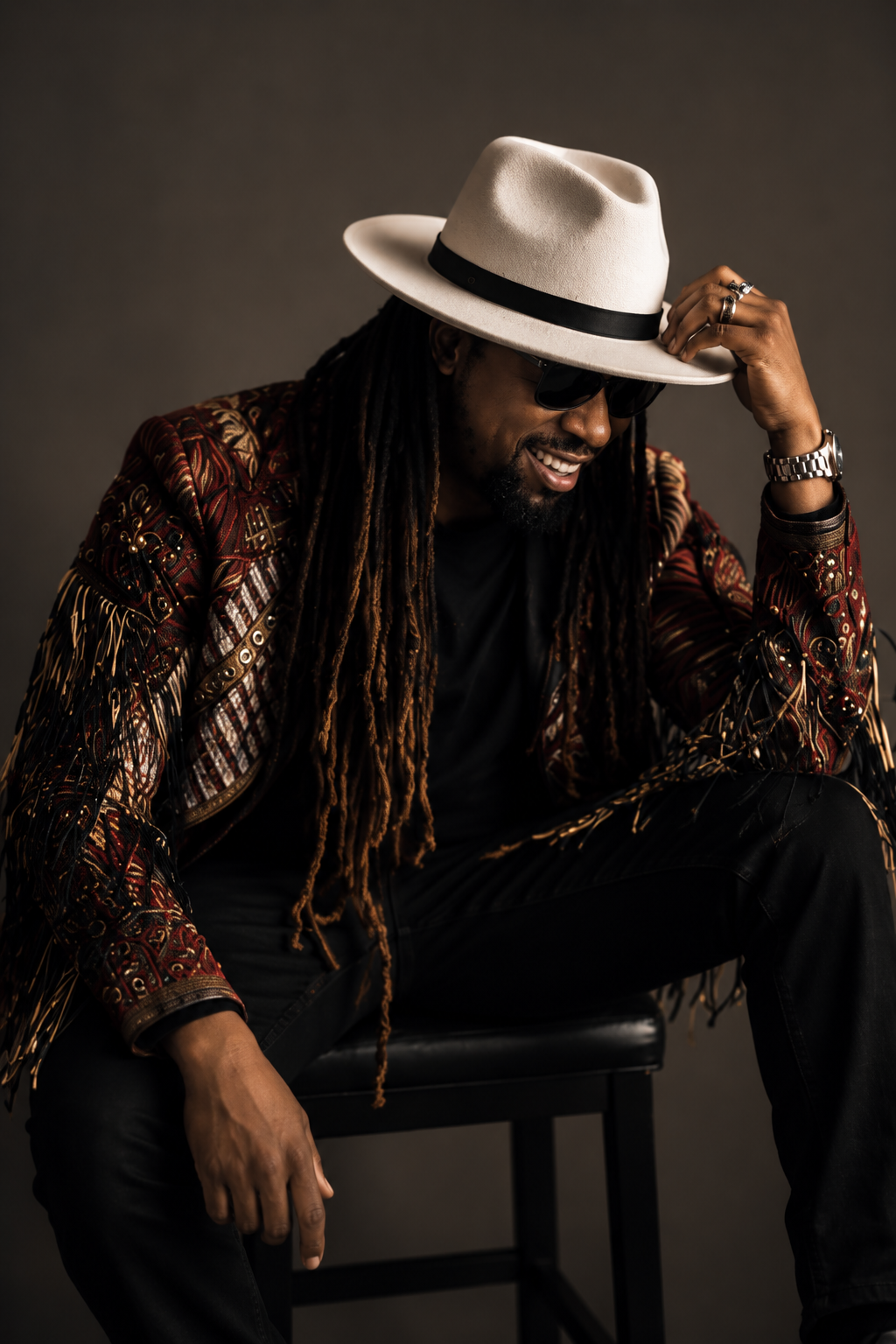 Brayo smiling in a white hat, shades and patterned jacket