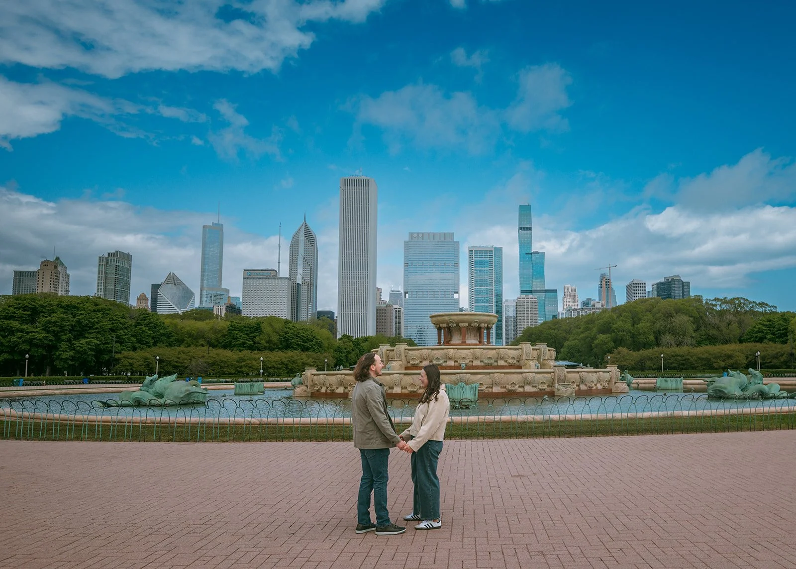 Engaged couple celebrating at Buckingham Fountain in Chicago after surprise proposal by Jeremy Glickstein Photography