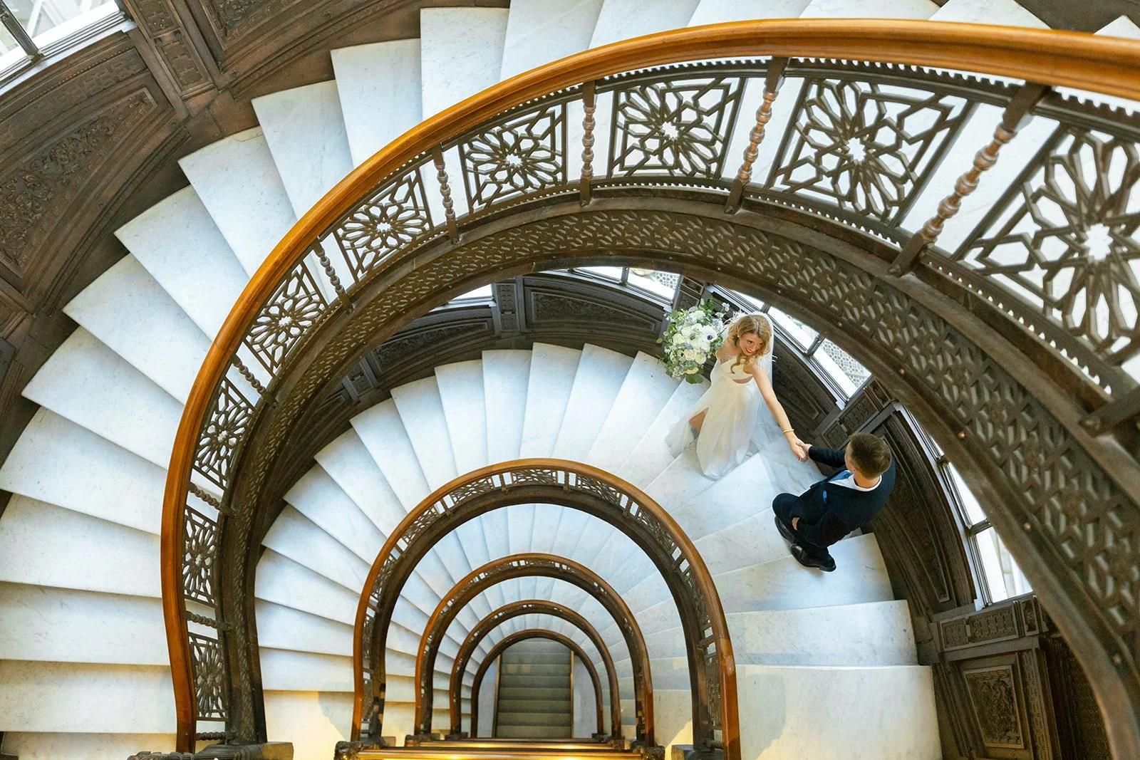 Iconic Rookery Building spiral staircase wedding portrait with bride descending marble stairs in Chicago
