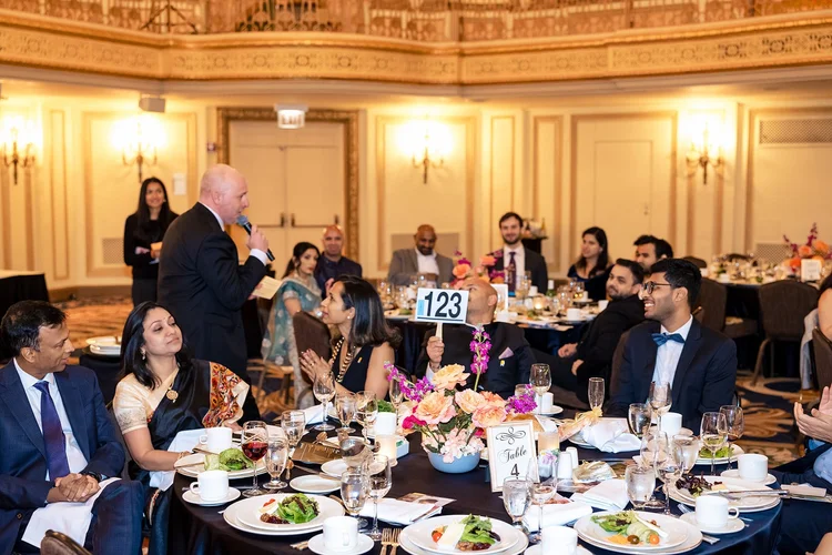 Pratham USA gala stage moment — Speaker addressing audience at fundraising event