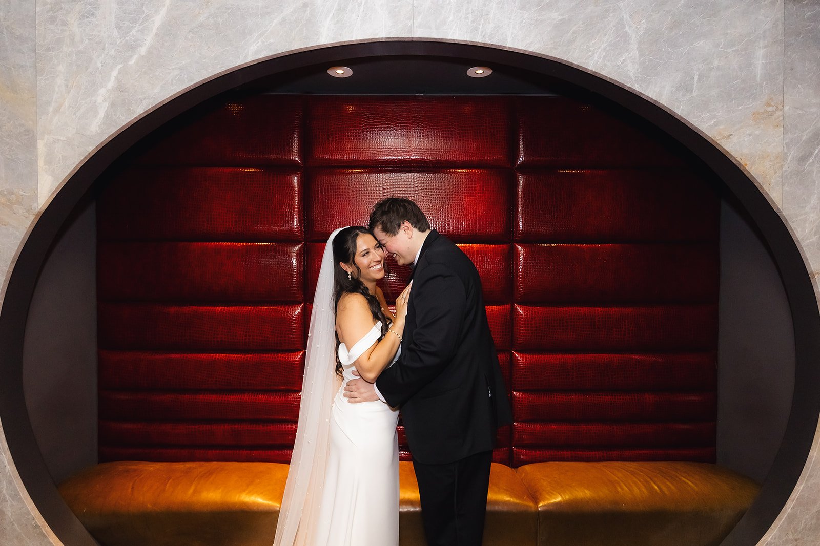 Stylish Chicago wedding portrait of bride and groom in retro red leather booth showcasing cinematic editorial photography style