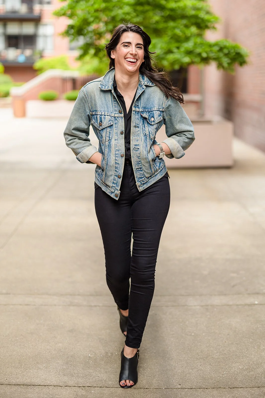 Woman in a denim jacket laughing as she walks down a Chicago courtyard path, dating profile photography by Jeremy Glickstein