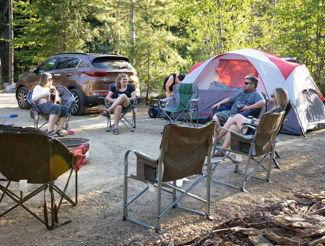 Friends relaxing in camp chairs beside their tent at a Crazy Creek campsite