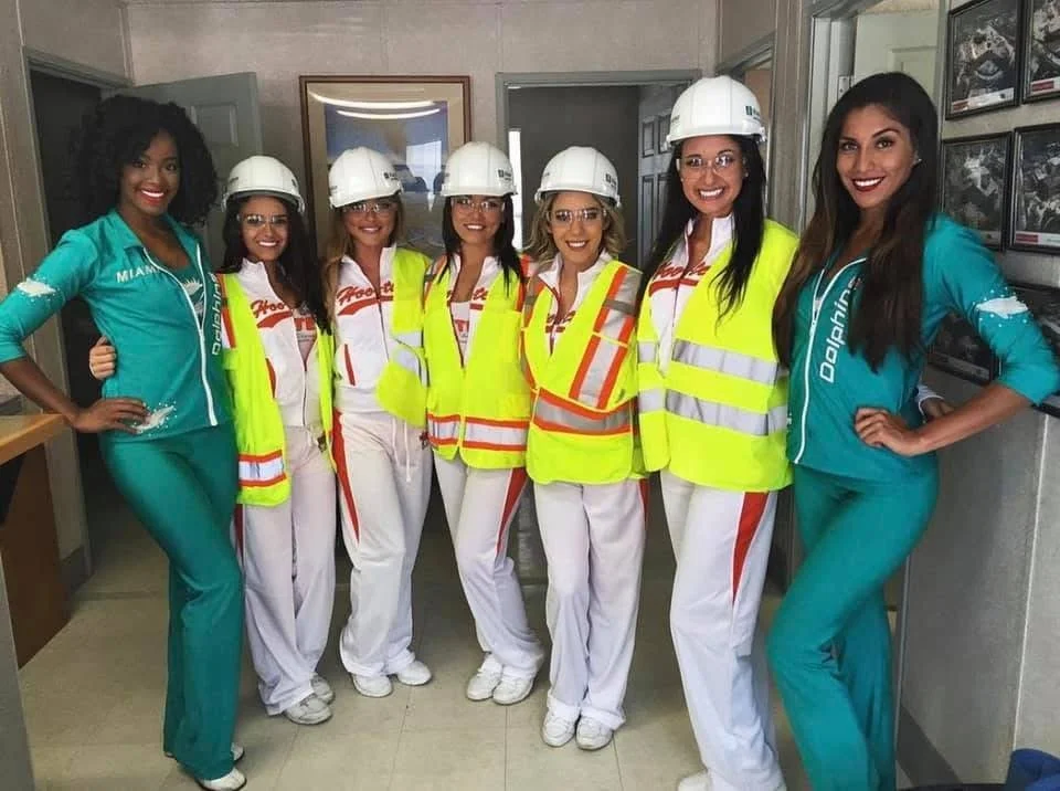 Victoria Ruiz and fellow Hooters Girls in hard hats and safety vests at a community event