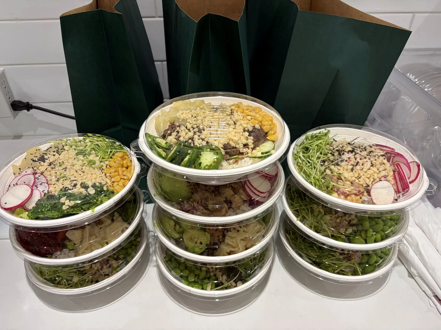 Pokerrito poke bowls packed in takeout containers with dark green Pokerrito bags, ready for the Fort Capital team lunch