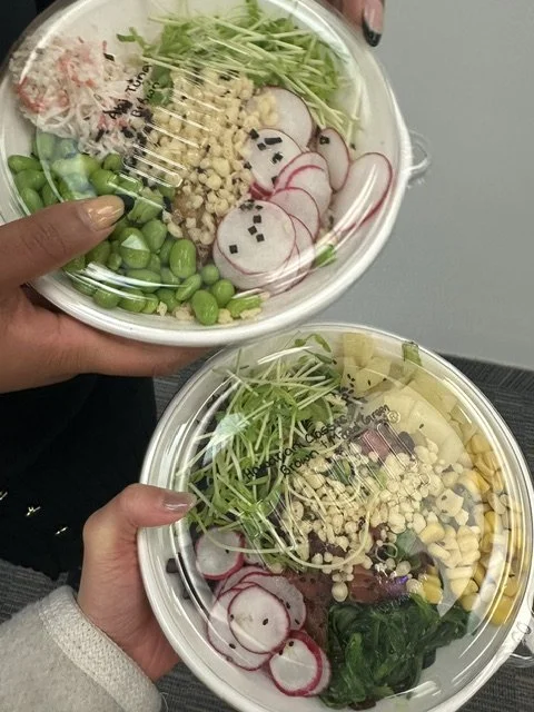 Two Pokerrito poke bowls held up at the office by a Financial District team