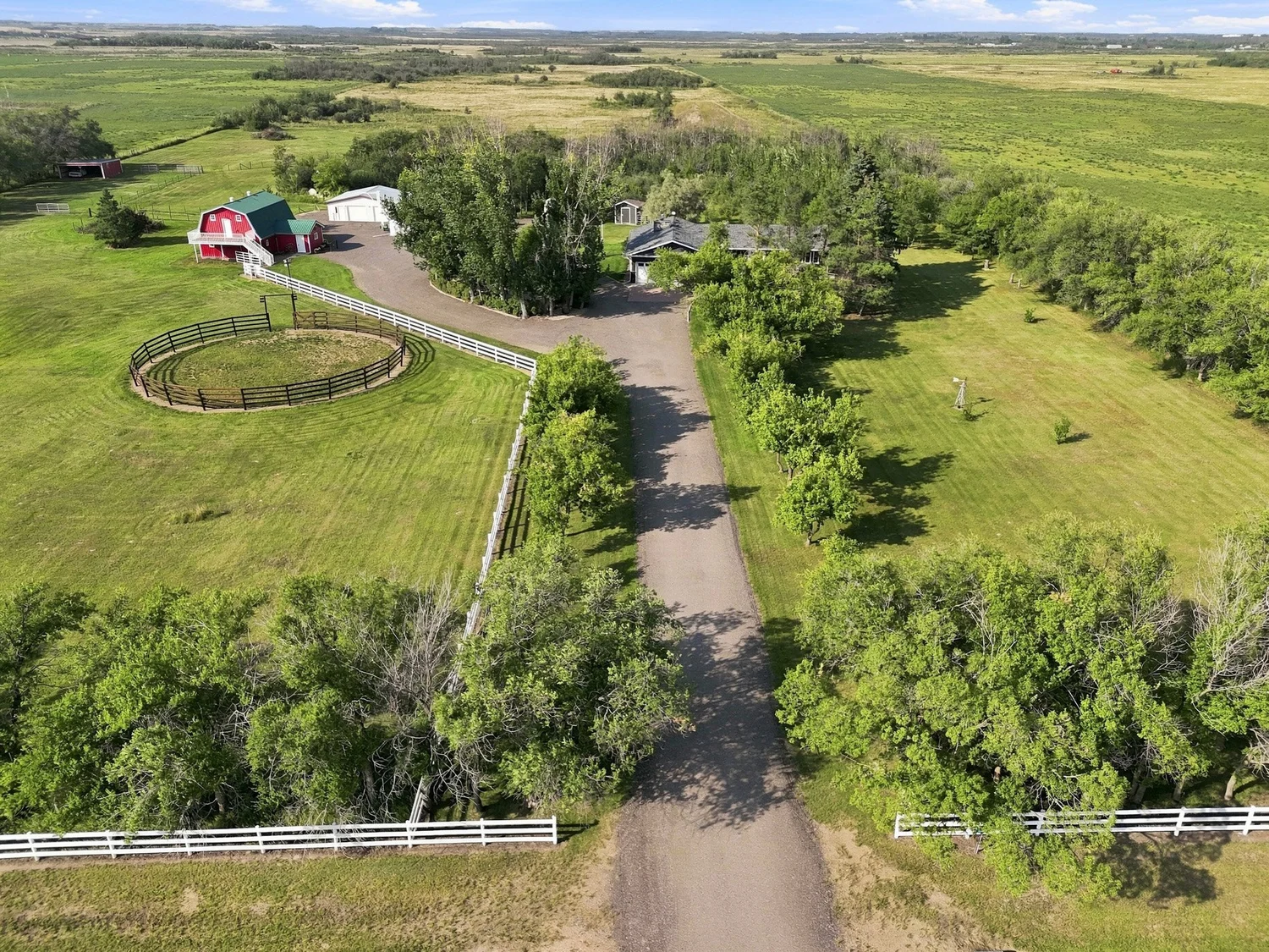 Aerial view along a rural driveway toward a home