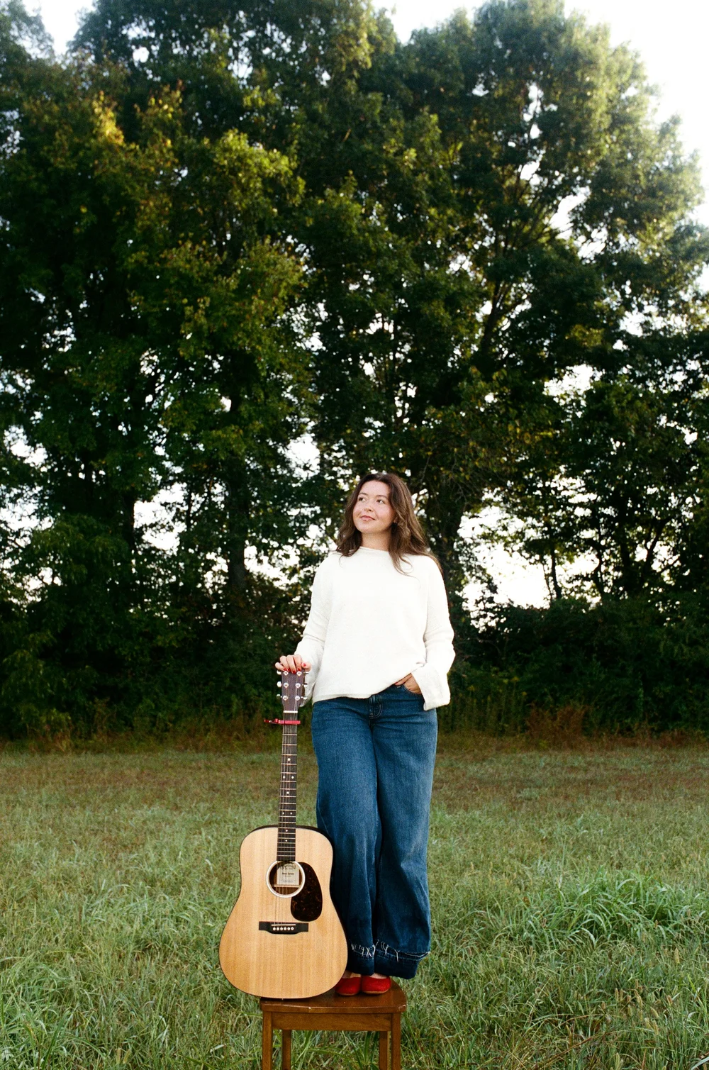 press photo: Katie standing beside her guitar