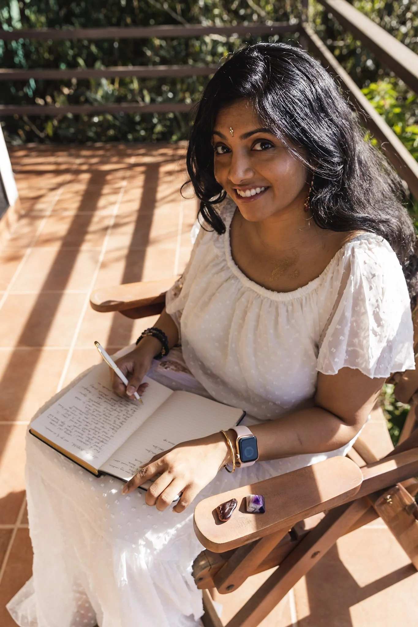 Nikhi Joshi journaling outdoors with crystals nearby