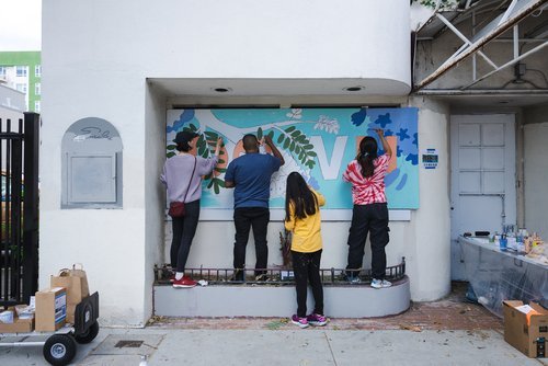 Volunteers work together to complete a mural in front of the old Emile's Restaurant.