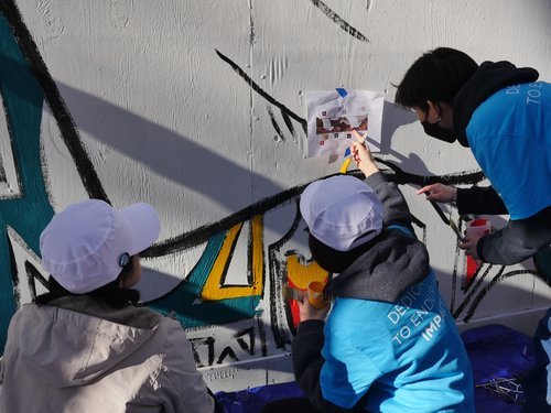 Volunteers work together to paint in a mural designed by artist Anthony Combs.