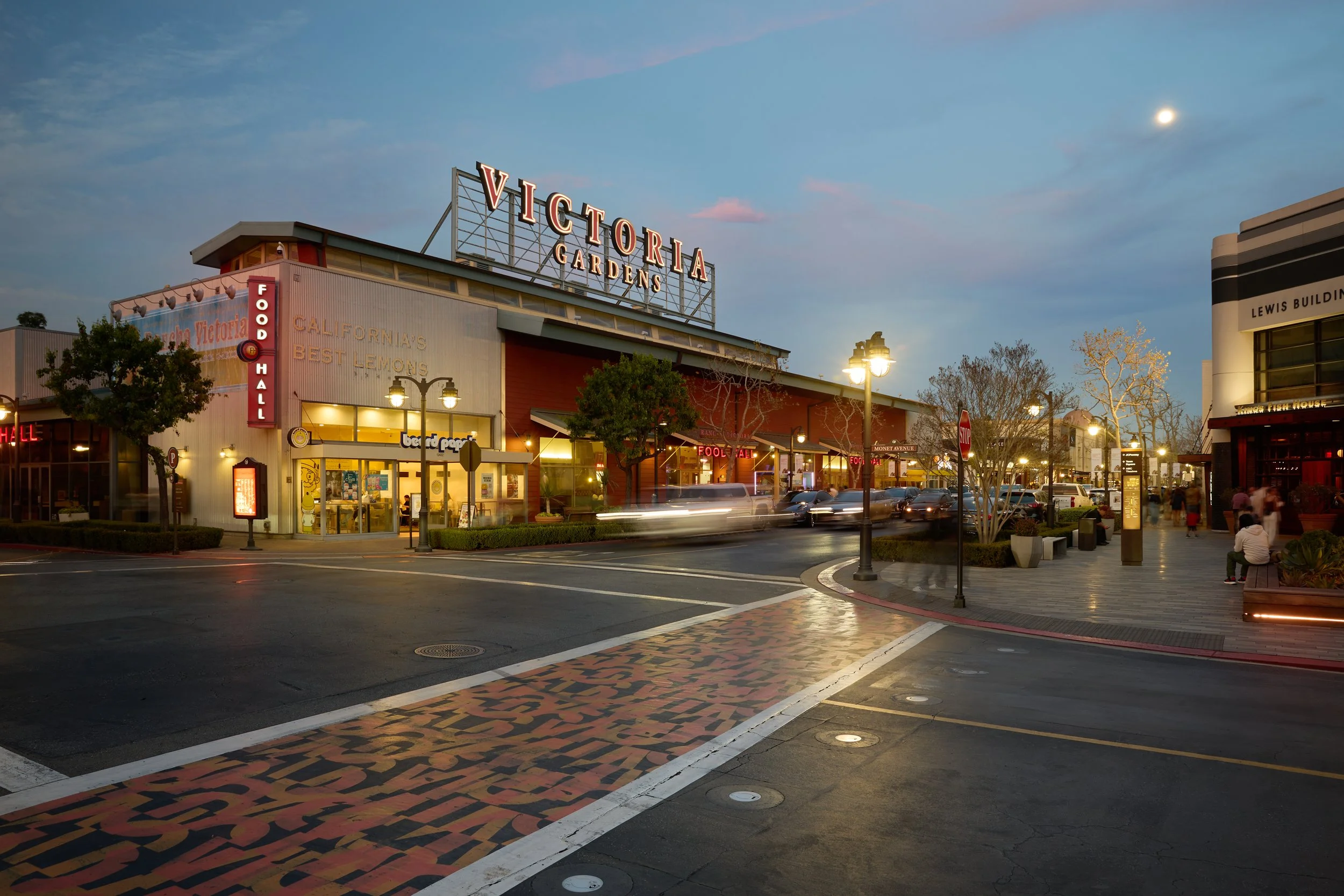 Victoria Gardens food hall and retail center at blue hour with illuminated signage and motion-blurred traffic, commercial property photography by Matt Francisco Los Angeles