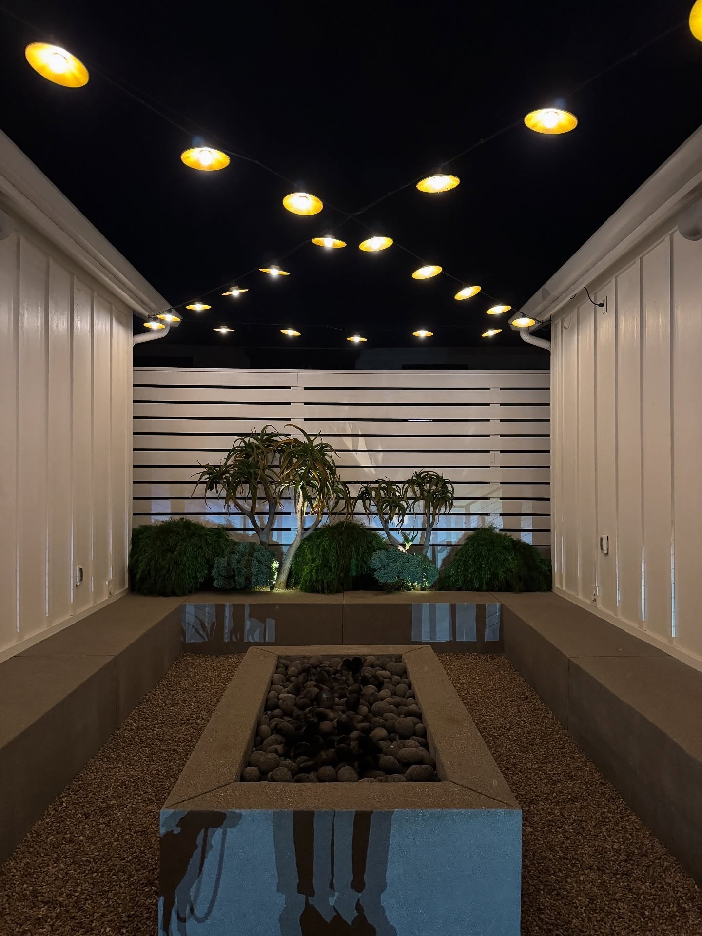 Covered passage at The Pacific Motel with round ceiling lights and a planted outdoor space.