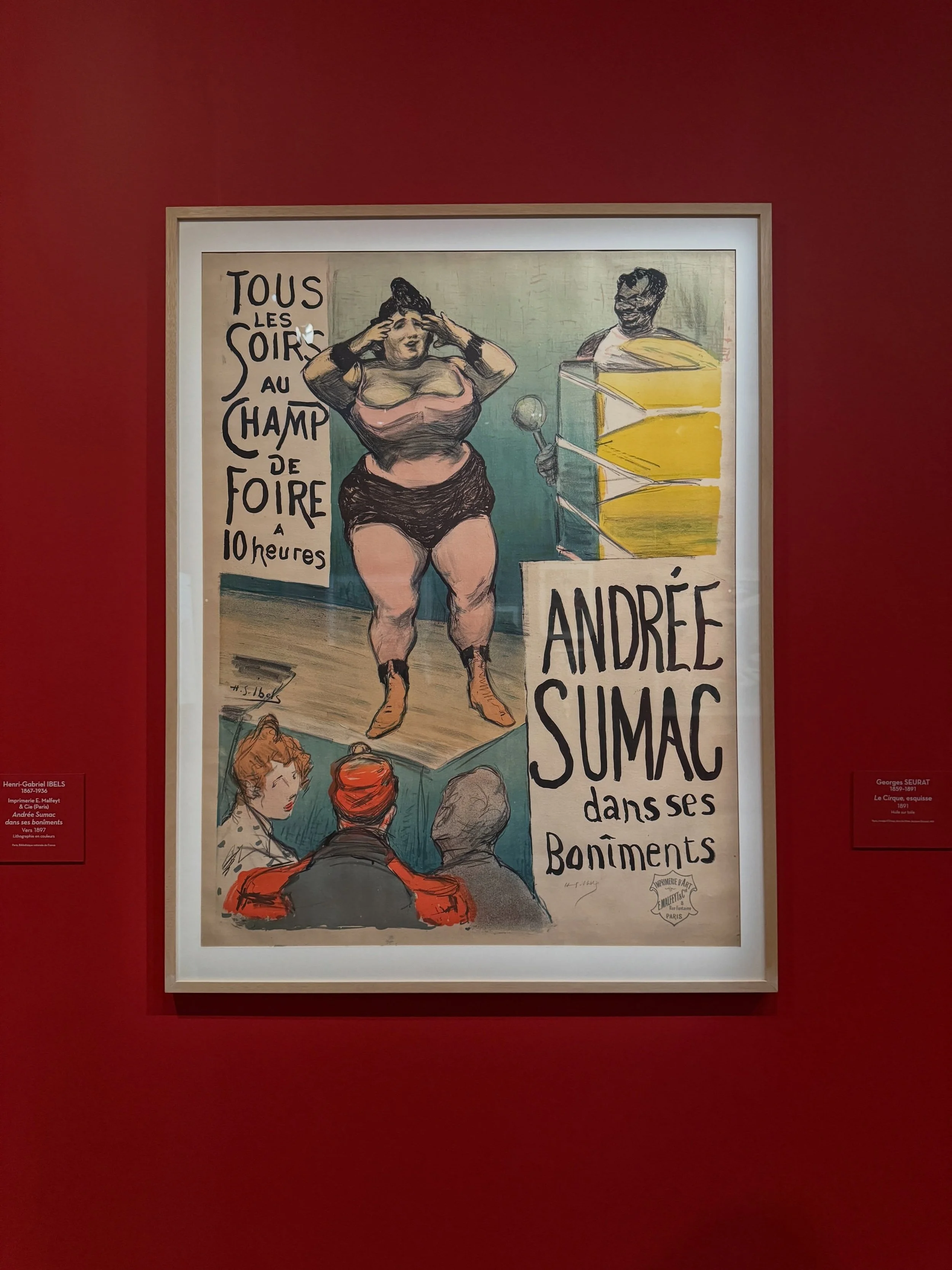 Framed vintage French performance poster against a red museum wall in Paris.