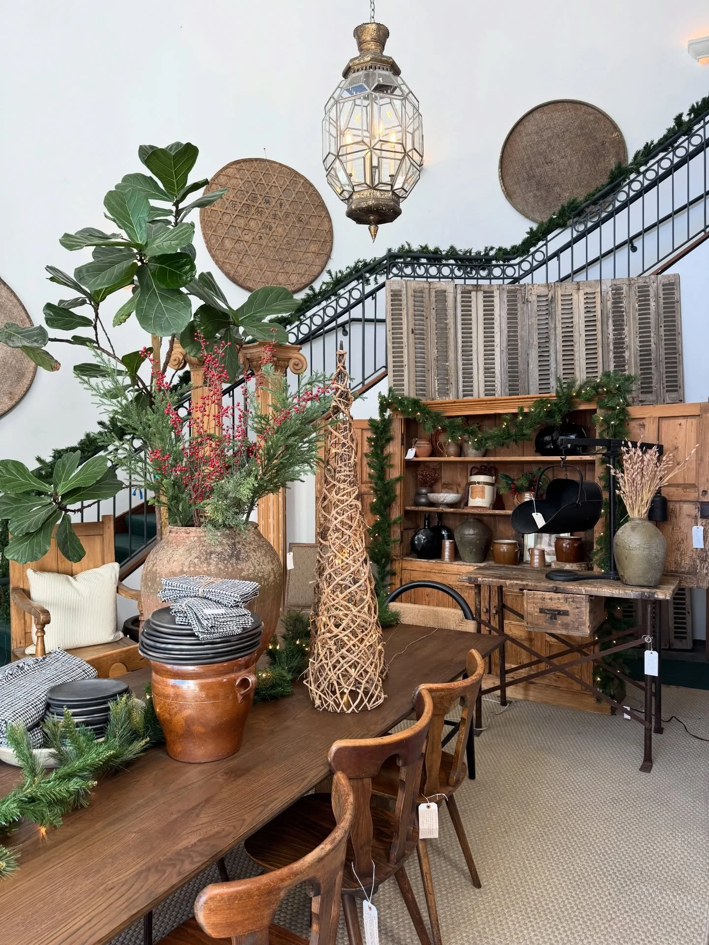 Vintage chairs, wood cabinets, hanging plants, and decorative lighting in a shop.
