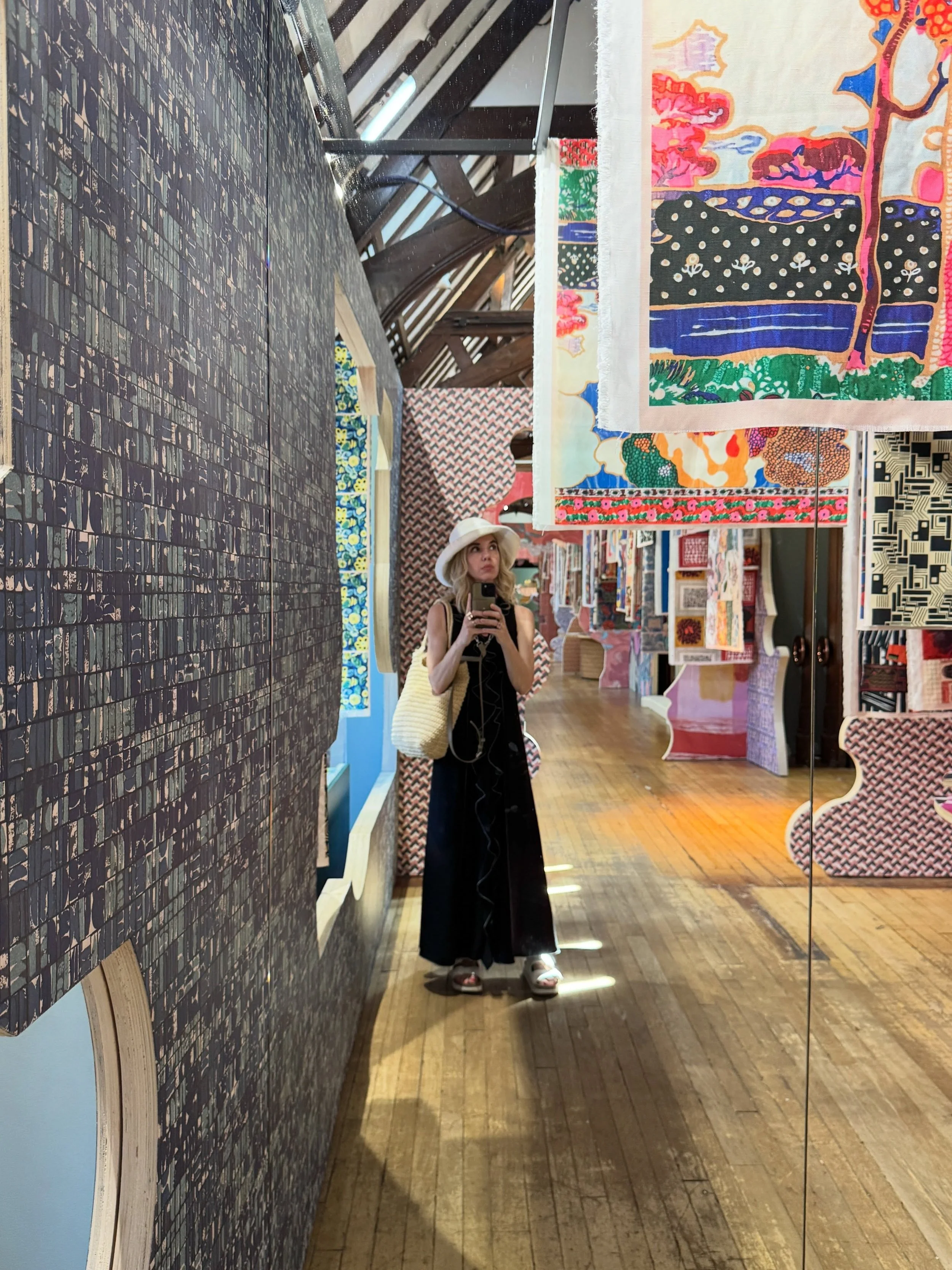 Printed fabric displays, patterned wallpaper, timber beams, and a shopper at Liberty London.