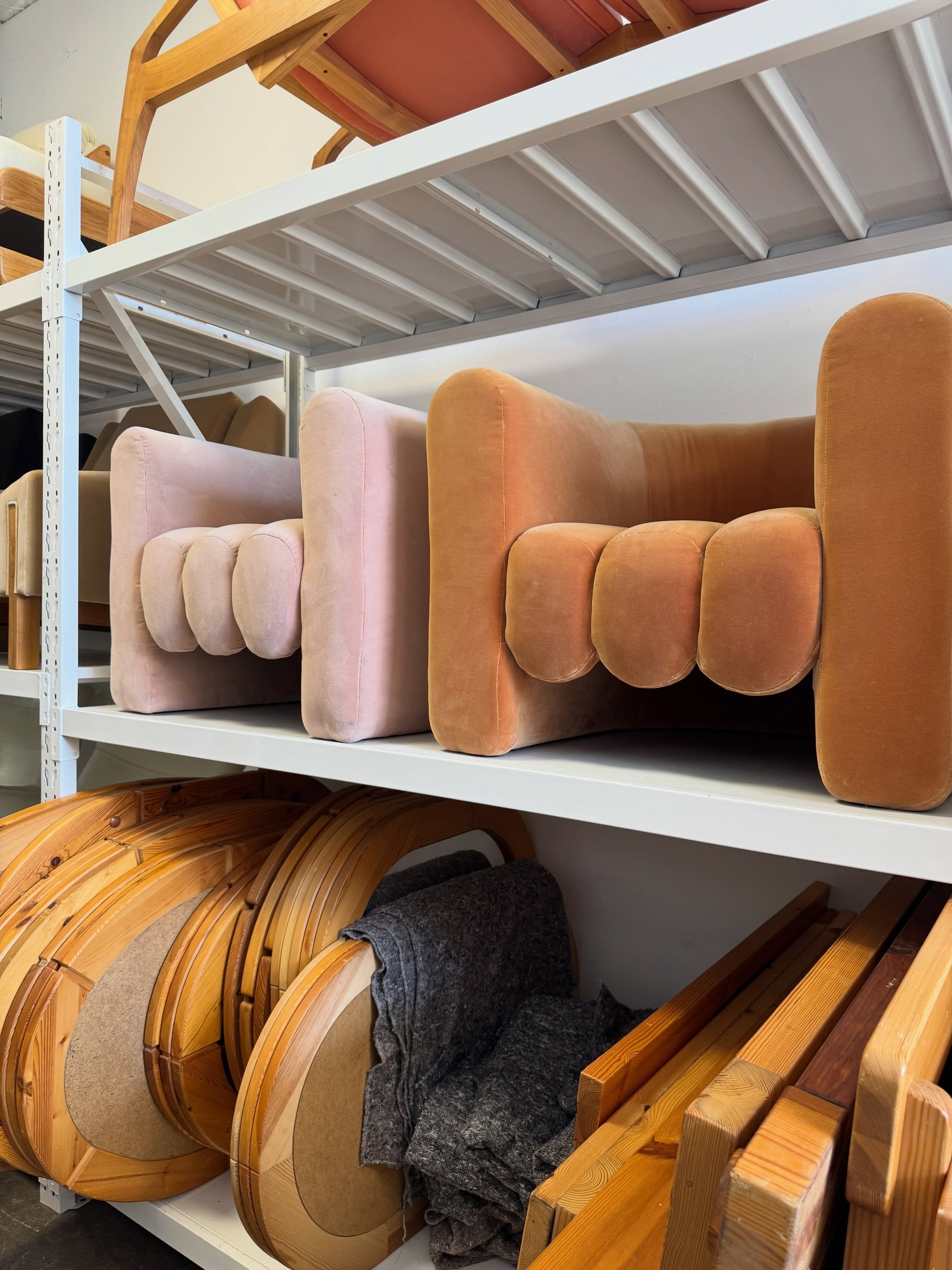 Sculptural upholstered chairs and wood forms displayed on showroom shelves.
