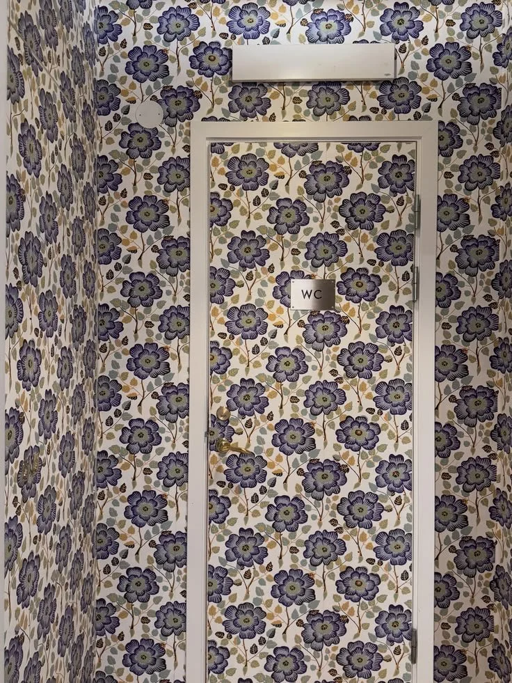 Doorway and walls covered in dense blue-and-cream floral wallpaper at Svenskt Tenn.
