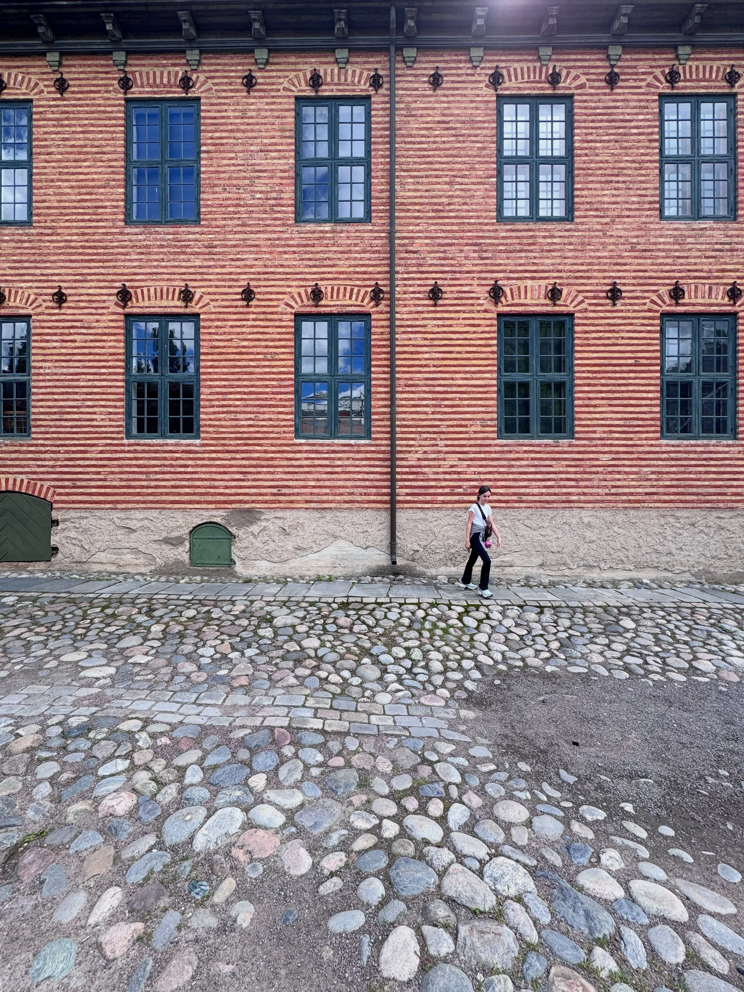 Red-brick historic building with blue windows and a cobbled courtyard in Oslo.
