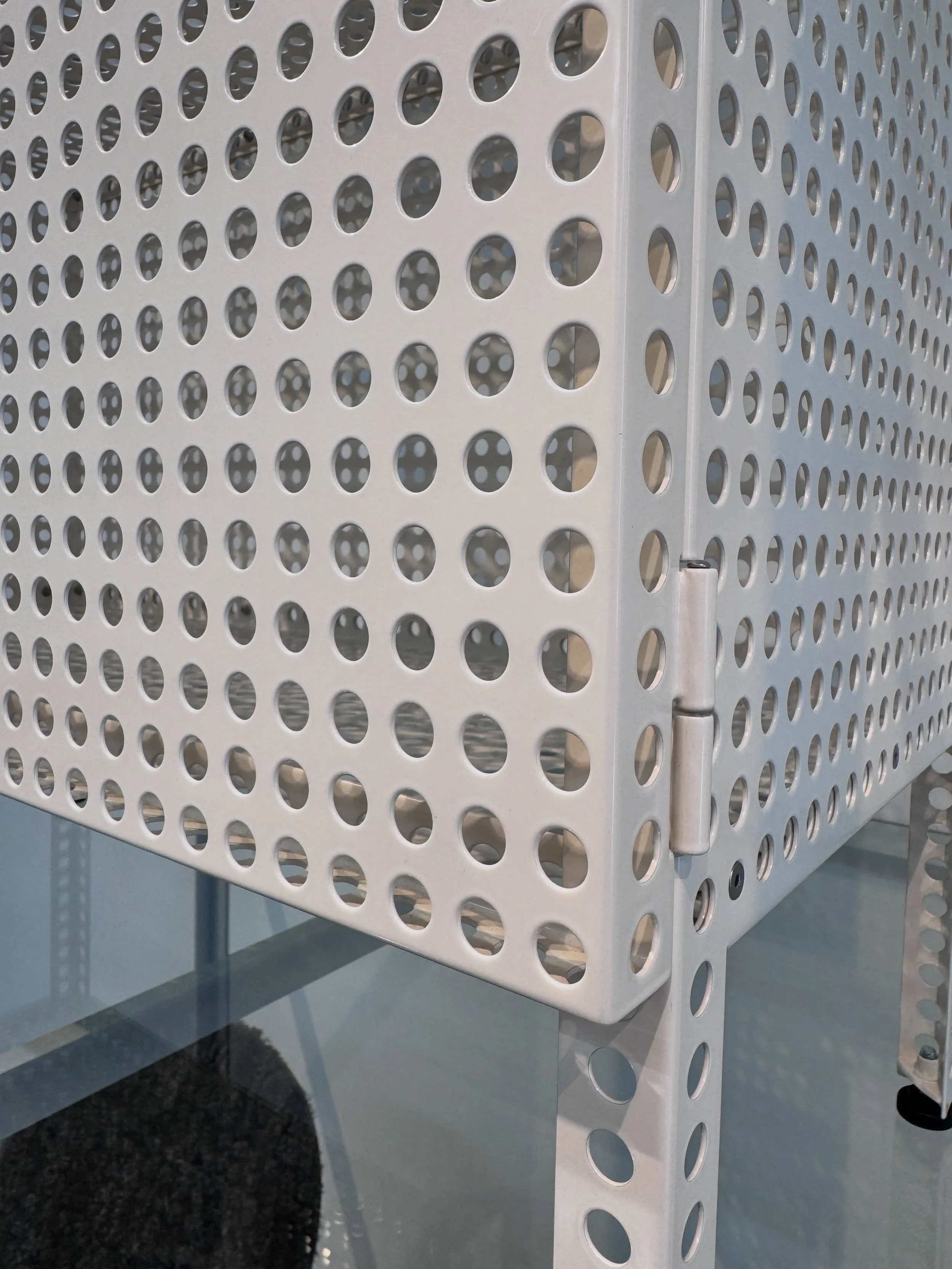 Perforated pale lighting shade casting a dotted shadow on the wall.