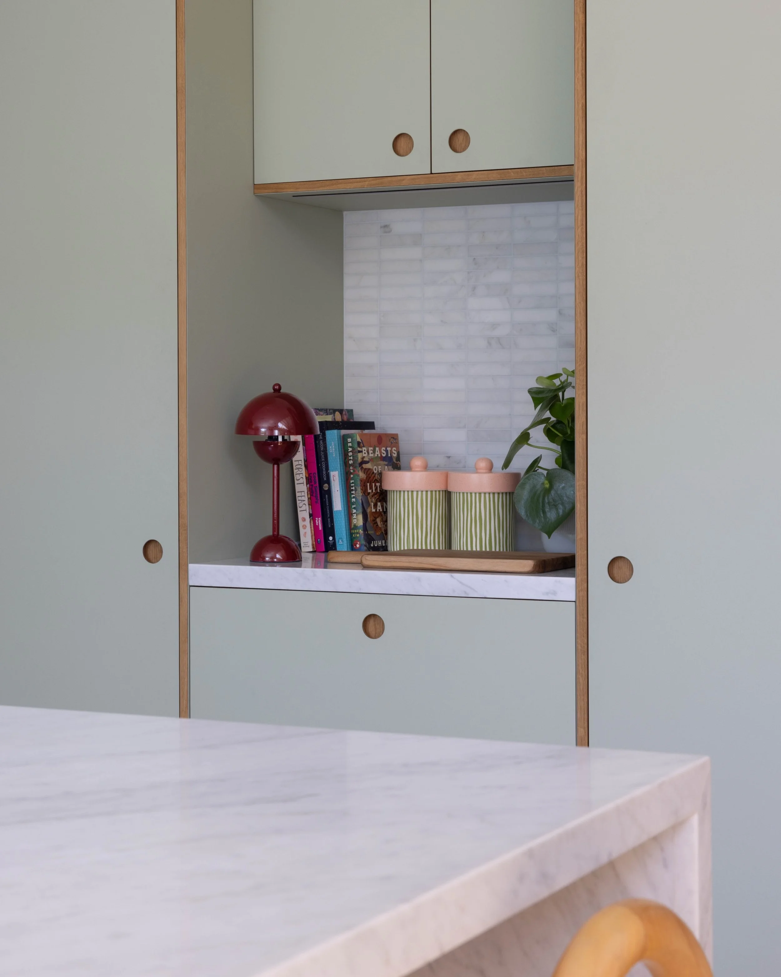 Styled kitchen counter with pale cabinetry, wood details, and decorative objects.