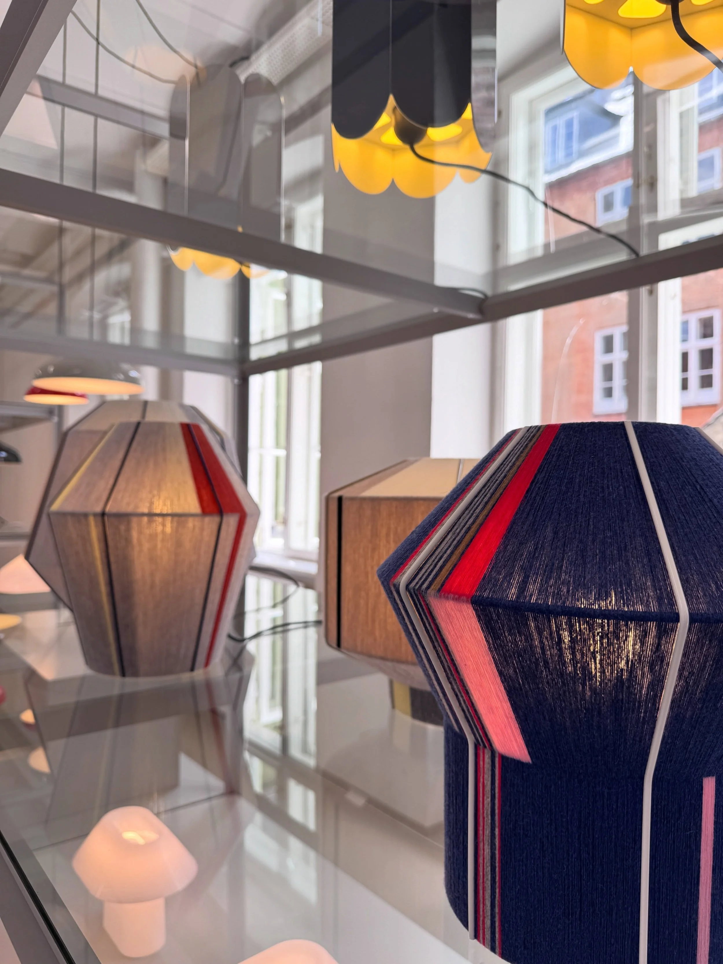 Colorful folded pendant shades displayed in a tall Copenhagen showroom window.