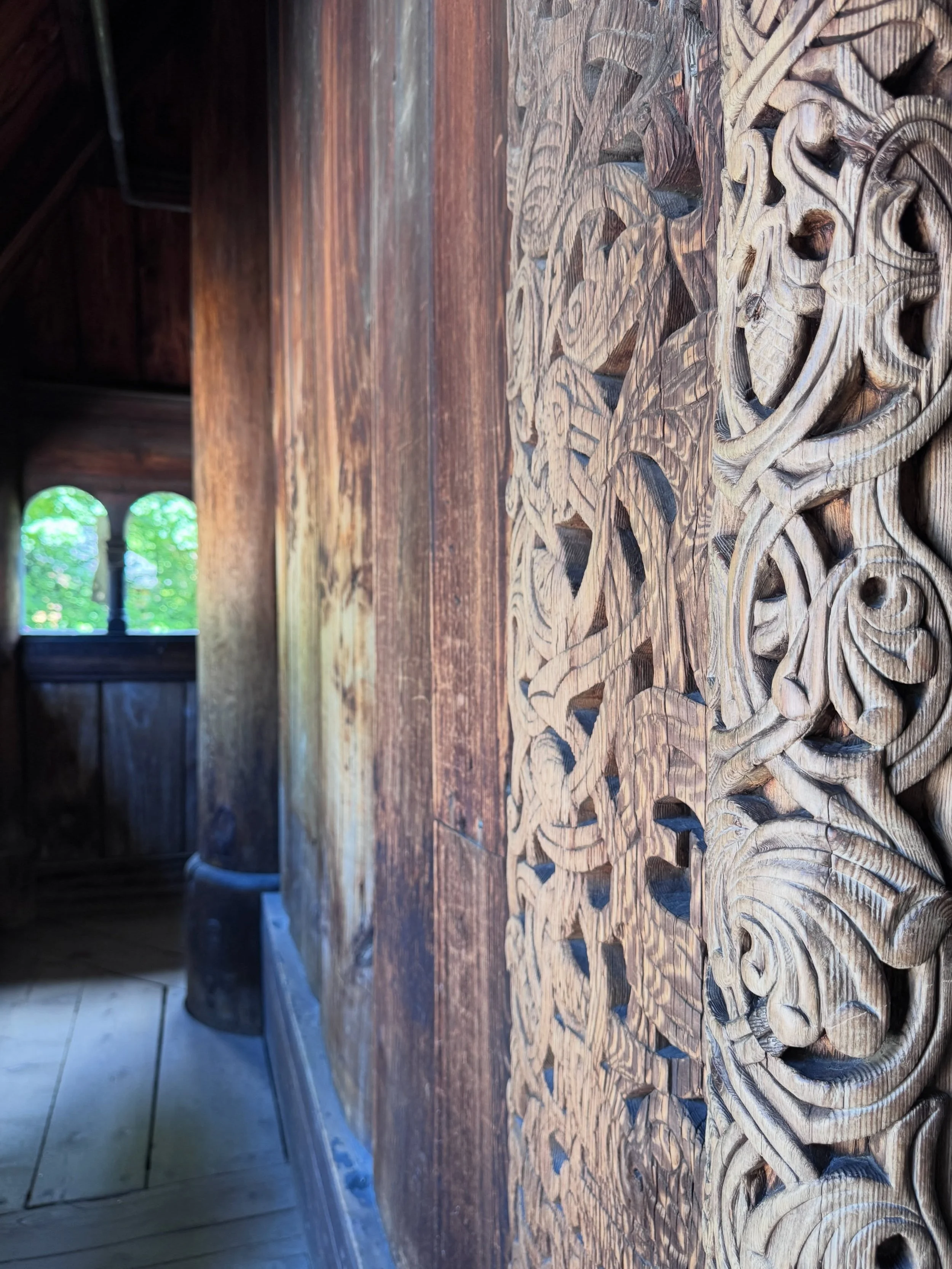 Intricately carved timber doorway, with an arched window visible inside.