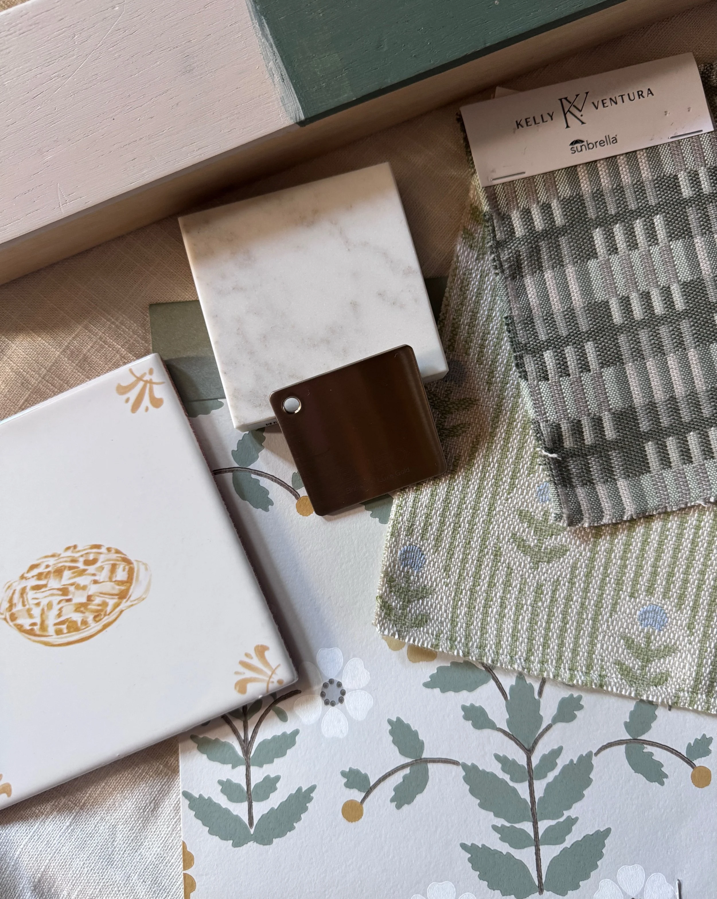 Interior design material board with stone, patterned fabric, wood, and paint samples.