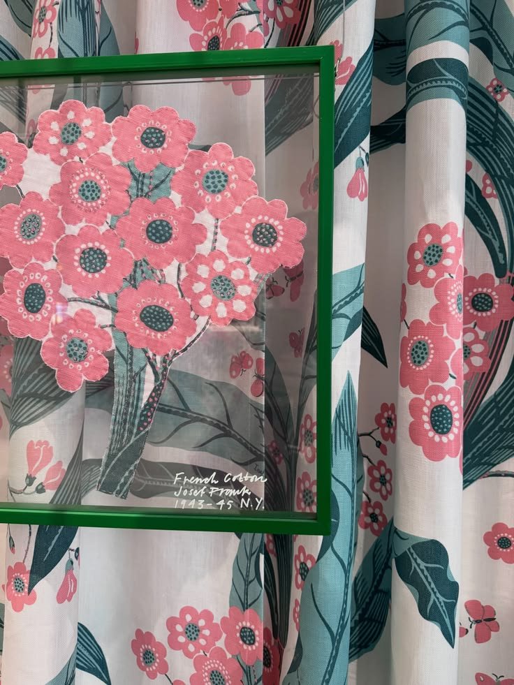 Pink floral textile displayed beside a green frame and coordinating printed curtain at Svenskt Tenn.
