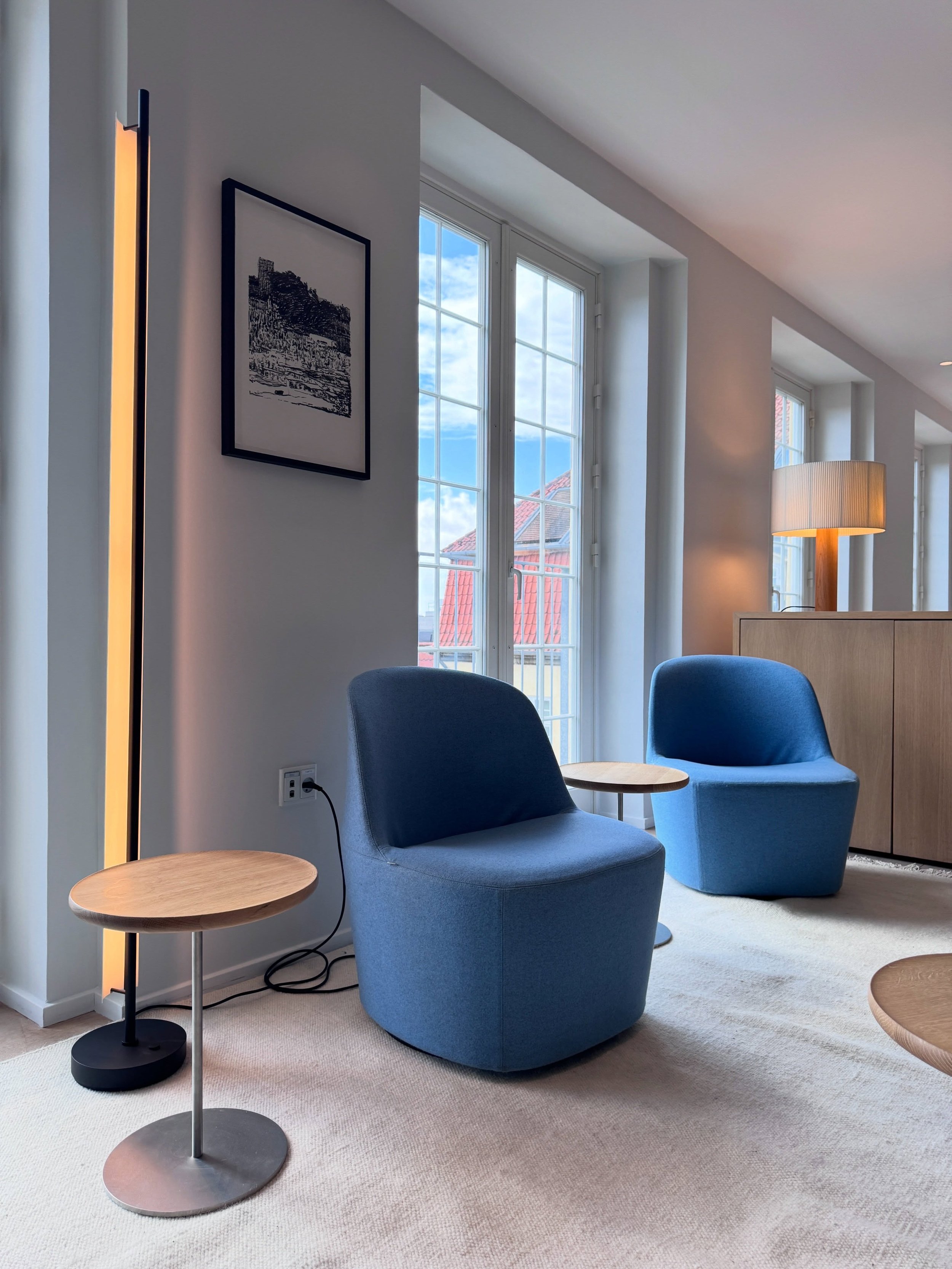 Blue upholstered armchairs beside tall windows in a Copenhagen design showroom.