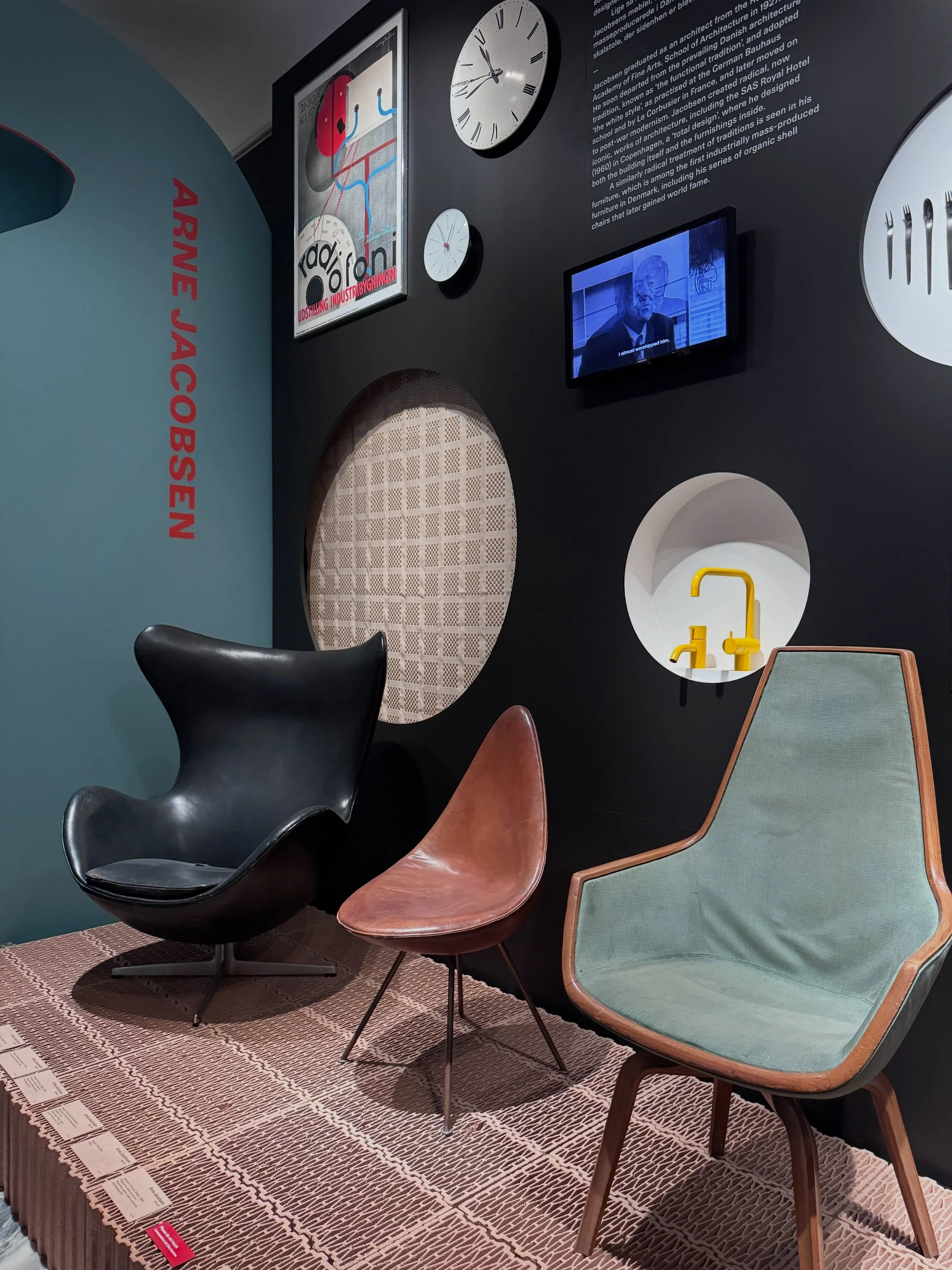 Sculptural chairs displayed against a dark wall at Designmuseum Danmark.