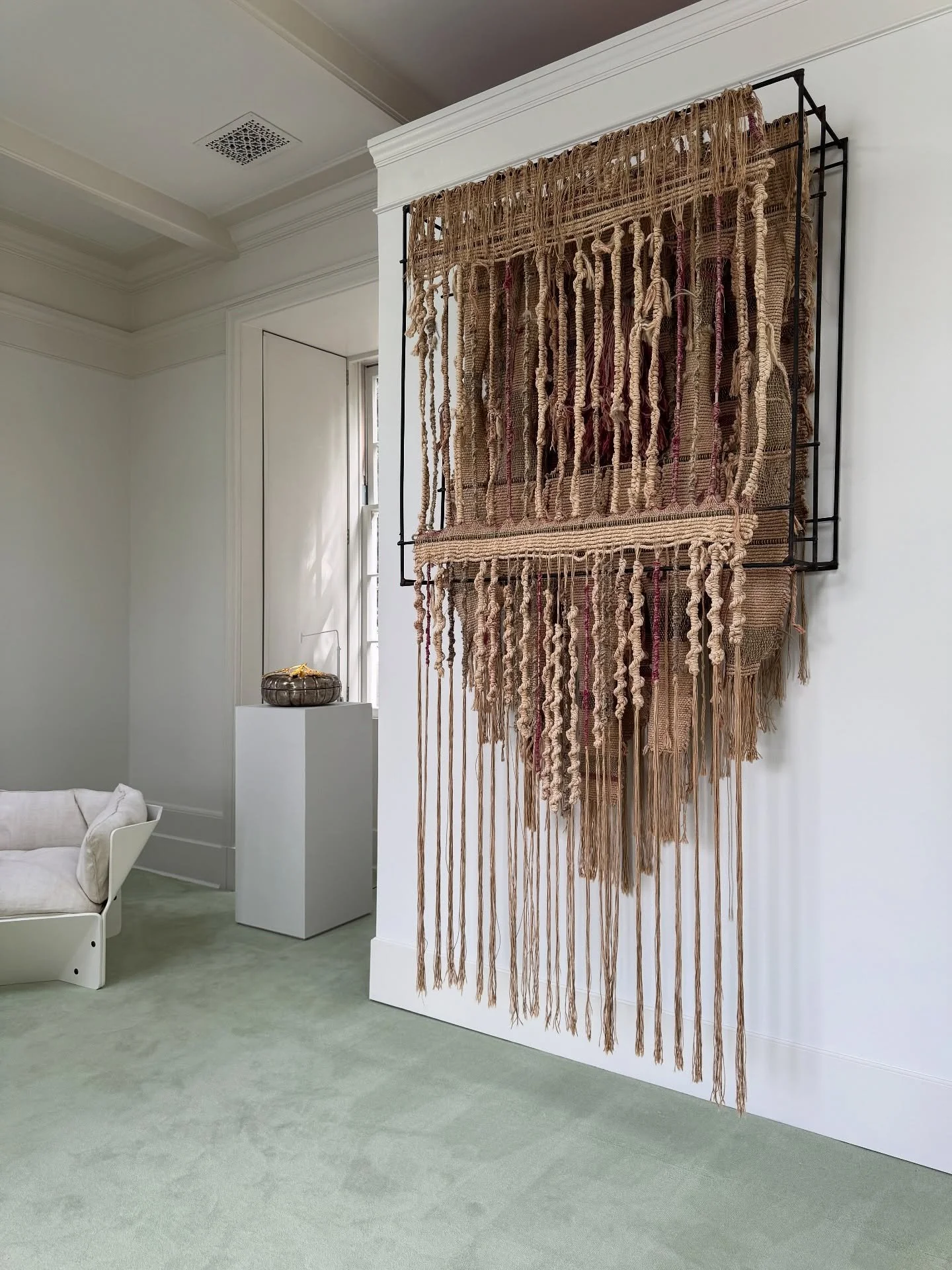 Large hanging fiber artwork with layered cords and fringe at Side Hustle Gallery.