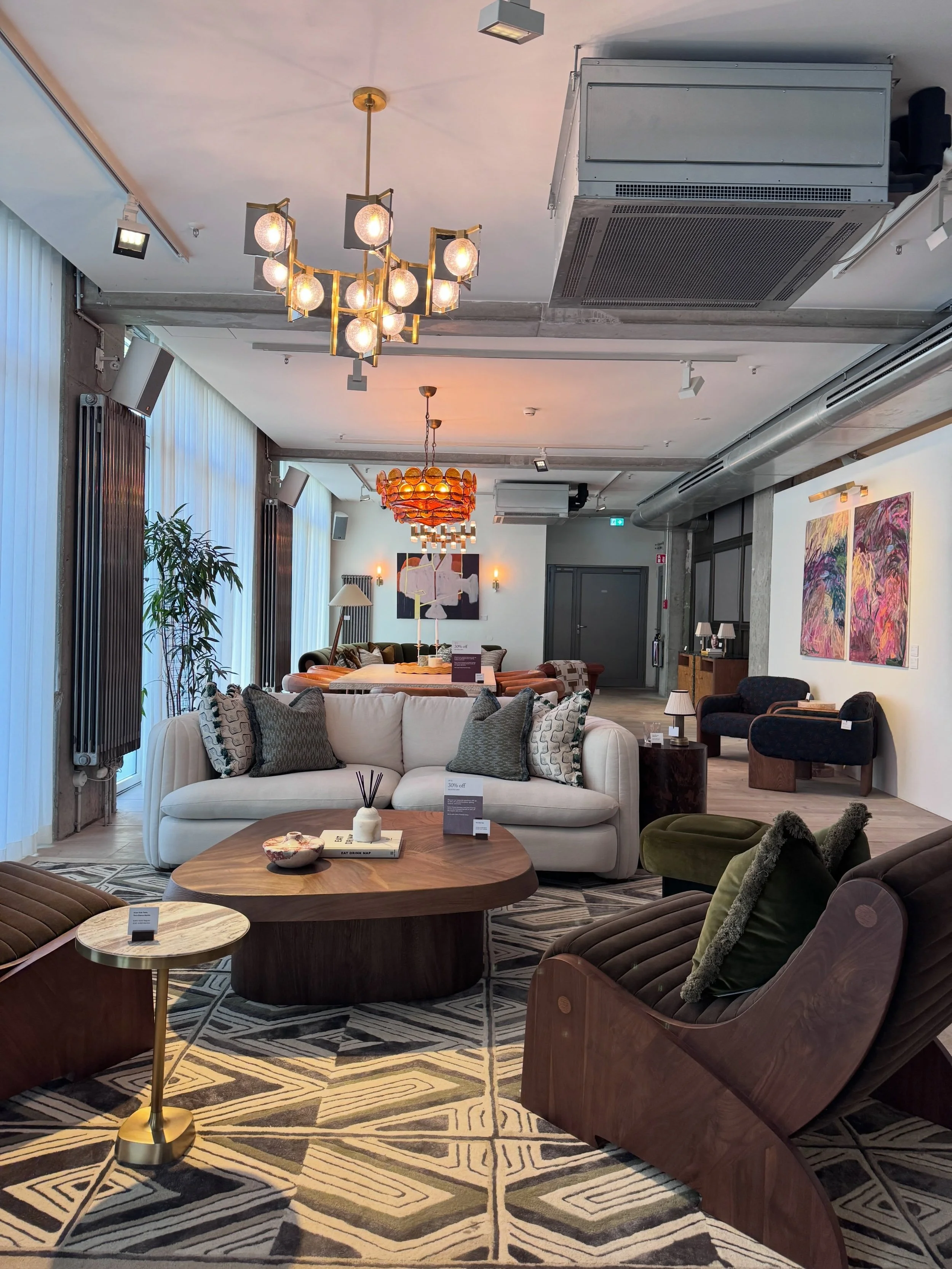 Soho House Berlin lounge with upholstered seating, patterned rugs, art, and a sculptural pendant.