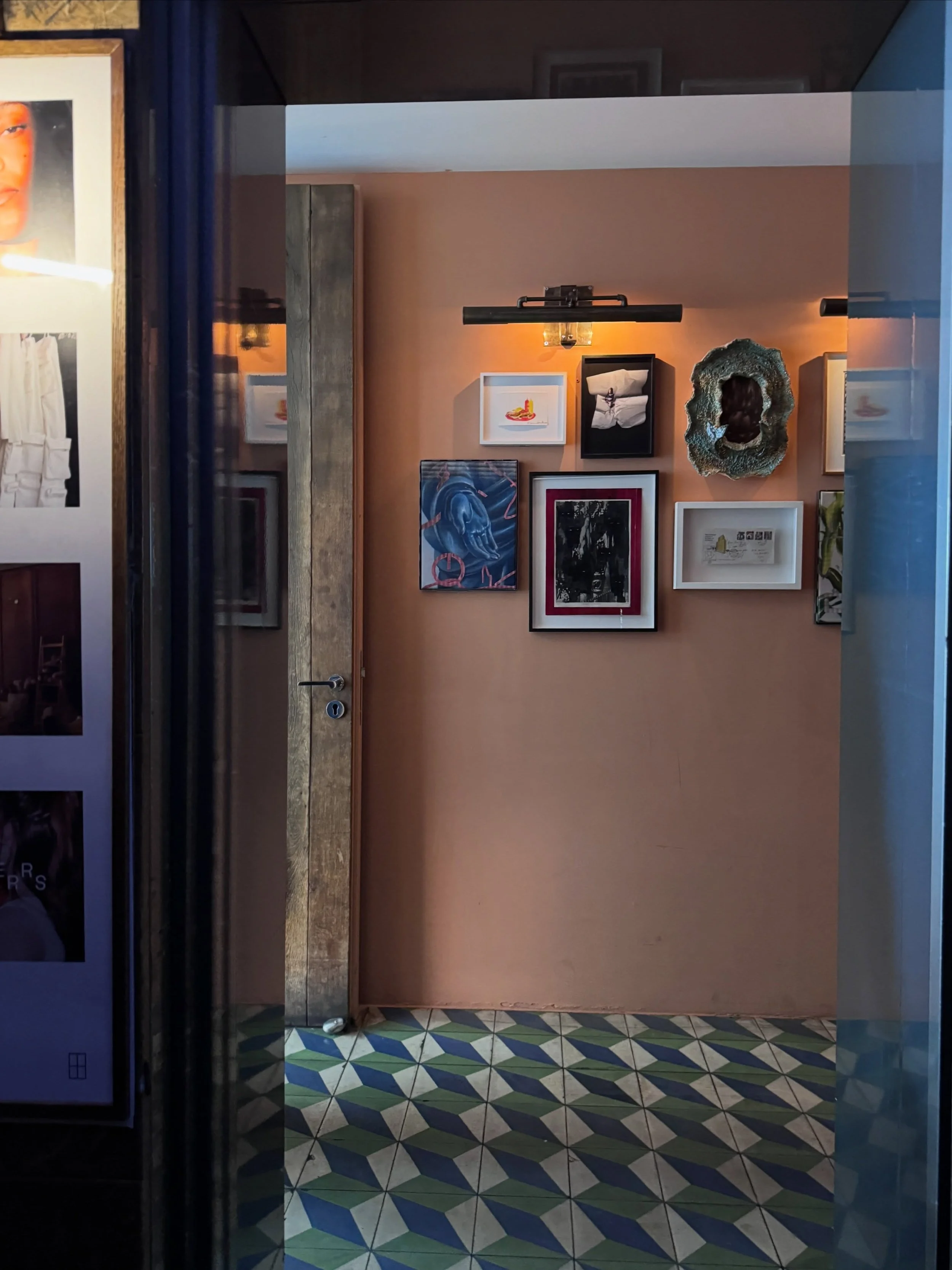 Soho House Berlin entry with framed art, wall lights, and a green-and-cream checkerboard floor.